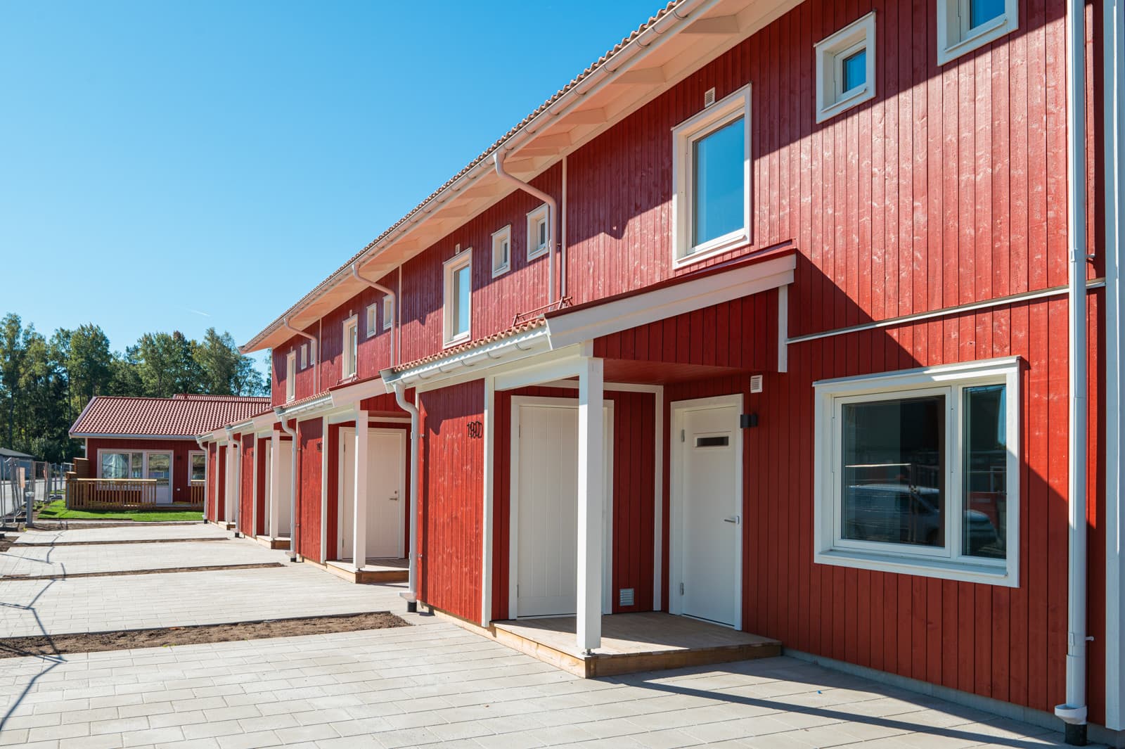 Bostäder utvecklade åt företagskund i Skogstorp, Eskilstuna. Entrébild med röd fasad.